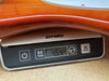 Close-up of a wooden guitar body resting on a Dymo digital scale showing the guitar weight as 4.544 kilograms.