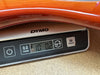 Close-up of Dymo digital scale showing 10 pounds 1.2 ounces weight of a guitar body with glossy orange finish on wood surface