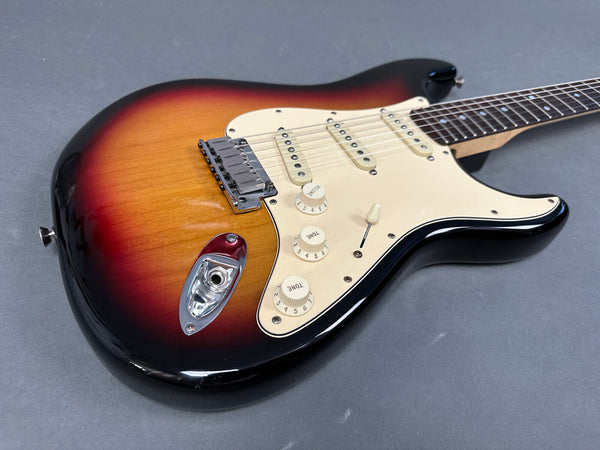 Sunburst electric guitar with three single-coil pickups, white pickguard, and chrome hardware on gray background