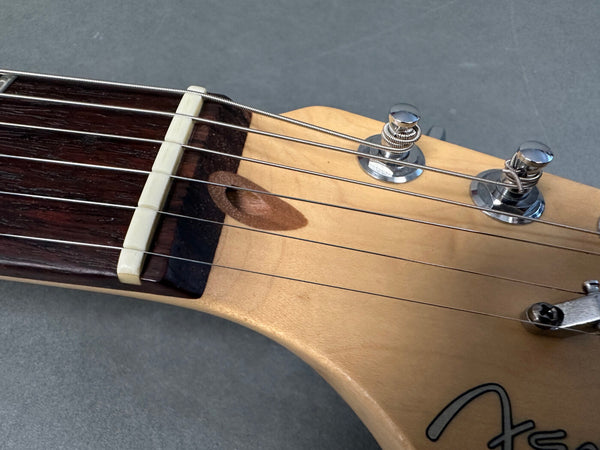 Close-up image of electric guitar headstock showing tuning pegs, nut, strings, and part of the fretboard on a gray background