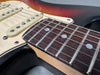 Close-up of electric guitar fretboard and strings on a sunburst body with cream pickguard and single coil pickups