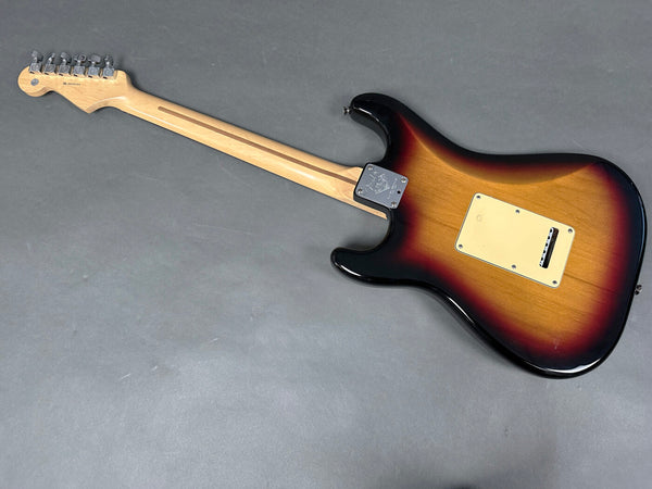 Back view of sunburst electric guitar with maple neck and chrome tuning pegs on gray background