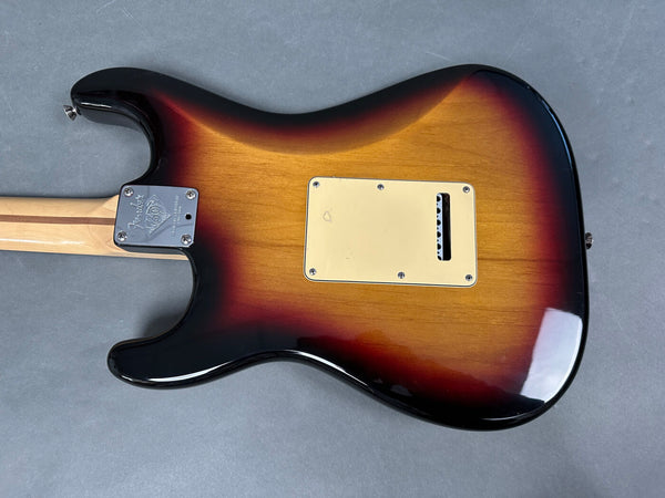Back of Fender electric guitar with sunburst finish and maple neck showing neck plate and tremolo cavity cover