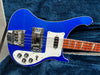 Electric bass guitar with blue body, white pickguard, chrome hardware, and wooden fretboard with rectangular inlays on blue plush background