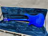 Electric bass guitar with blue finish inside blue plush-lined hard case showing the back of the instrument and tuning pegs