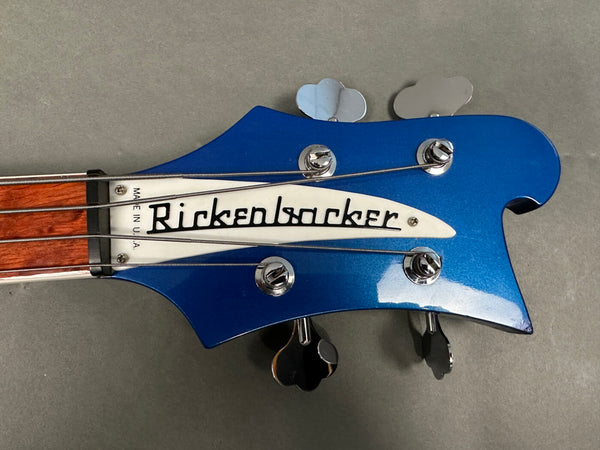 Close-up of blue Rickenbacker electric bass guitar headstock with four tuning pegs and Rickenbacker logo plate, made in USA visible on neck.