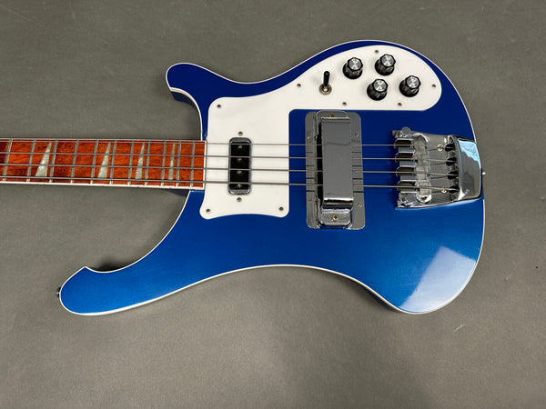 Blue electric bass guitar with white pickguard, four control knobs, and rosewood fingerboard on gray background
