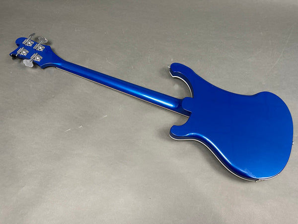 Back view of electric bass guitar in metallic blue finish with chrome tuning pegs on grey background