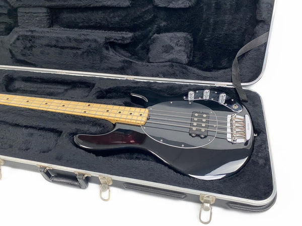Black electric bass guitar with maple neck and chrome hardware in black plush-lined hard case, four-string bass guitar case interior