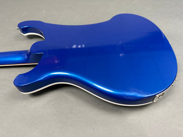 Back view of electric guitar with glossy metallic blue finish and cream binding on gray background