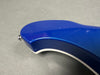 Close-up of blue electric guitar body edge showing minor paint chips and strap button on gray background