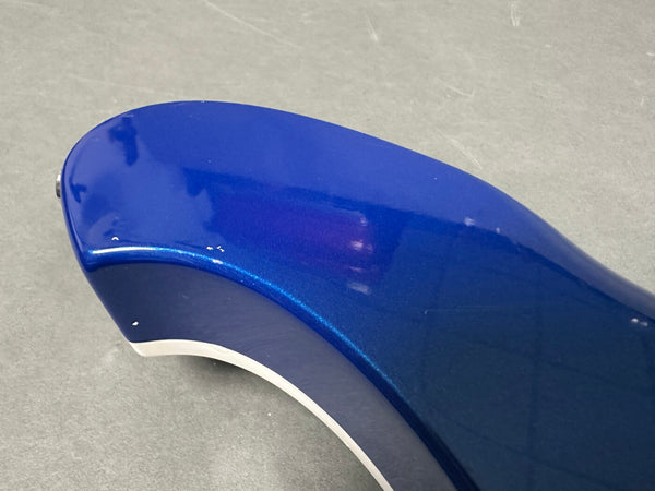 Close-up of the blue metallic finish on the body of an electric guitar showing minor wear and chips on the edge