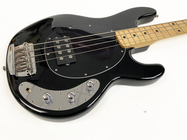 Black electric bass guitar with maple fretboard, chrome bridge, and control knobs on white background