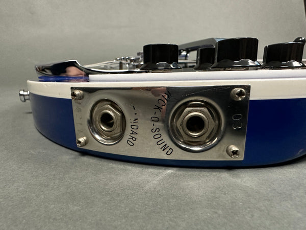 Close-up view of vintage guitar input jack plate with dual output jacks labeled "Nick-O-Sound" and "Standard" on blue and white electric guitar body