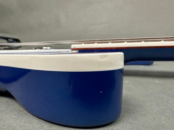 Close-up of blue and white acoustic guitar body showing minor dent and scratches on the edge near the neck and fretboard