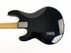 Back view of black electric guitar with natural wood neck and silver neck plate on white background