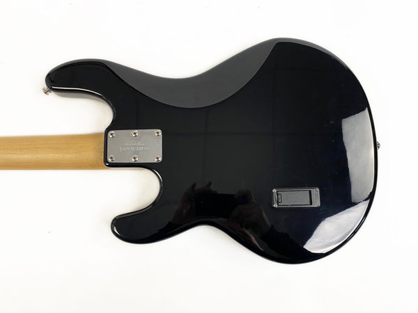 Back view of black electric guitar with natural wood neck and silver neck plate on white background