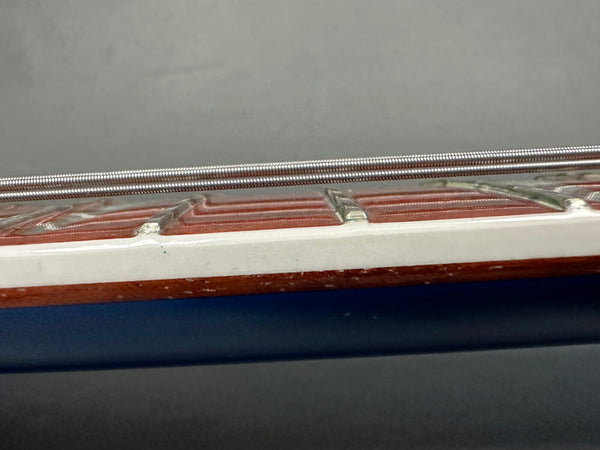 Close-up of acoustic guitar fretboard edge showing wound guitar string, frets, and binding detail