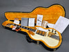 Vintage Gibson SG electric guitar in white with gold hardware lying in an open black hardshell case with orange plush interior, accompanied by Gibson Gold Warranty, certificate of authenticity, and Coffee House Guitars pre-sales checklist and tags