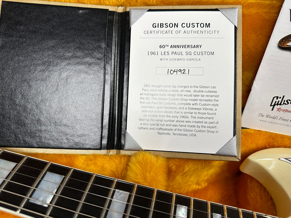Gibson Custom Certificate of Authenticity for 60th Anniversary 1961 Les Paul SG Custom guitar with sideways Vibrola, serial number 104921, displayed with guitar neck and gold plush case interior.