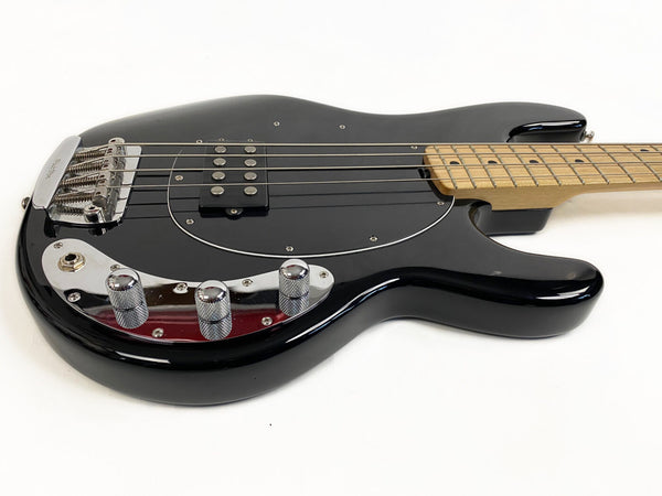 Black electric bass guitar with maple neck, chrome bridge, and control knobs on white background