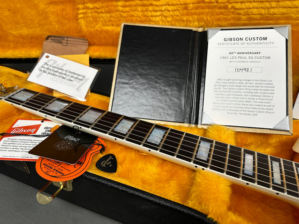 Close-up of Gibson Custom 60th Anniversary 1961 Les Paul SG Custom guitar certificate of authenticity and guitar neck with tags inside black and yellow plush-lined hard case