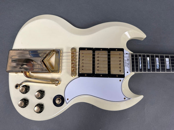White Gibson Les Paul Custom electric guitar with gold hardware, triple humbucker pickups, Vibrola tailpiece, and white pickguard on gray background