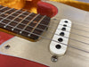 Close-up of electric guitar bridge and strings with metal pickguard and rosewood fretboard on red body