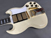 Vintage white electric guitar close-up showing three gold humbucker pickups, white pickguard, gold bridge and vibrato tailpiece, black control knobs on gray background
