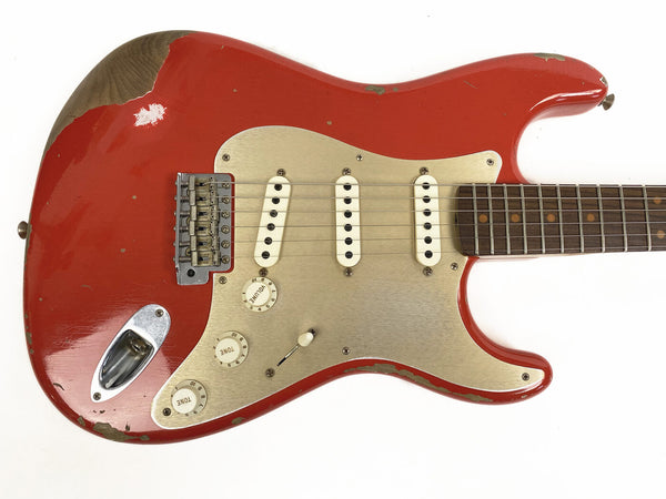 Vintage red electric guitar with worn paint and cream pickguard, three single-coil pickups, and rosewood fretboard on white background