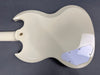 Cream white electric guitar back body with double cutaway design and control cavity cover plate on dark gray background