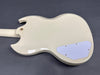 Glossy white electric guitar back with white control cavity cover and gold screws on gray background