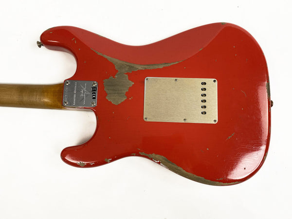 Back of worn red Fender Stratocaster electric guitar showing relic finish and metal neck plate with serial number, against white background