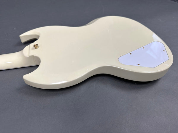 Back view of cream-colored electric guitar body with white control cavity cover and gold strap button on gray background