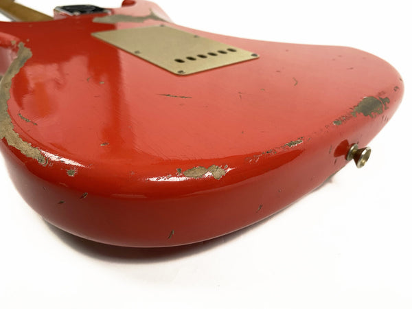 Close-up of vintage red electric guitar body with worn and chipped paint showing aged relic finish on white background