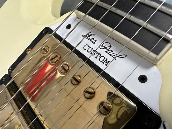 Close-up of Les Paul Custom guitar pickup with gold cover and white pickup ring on cream guitar body