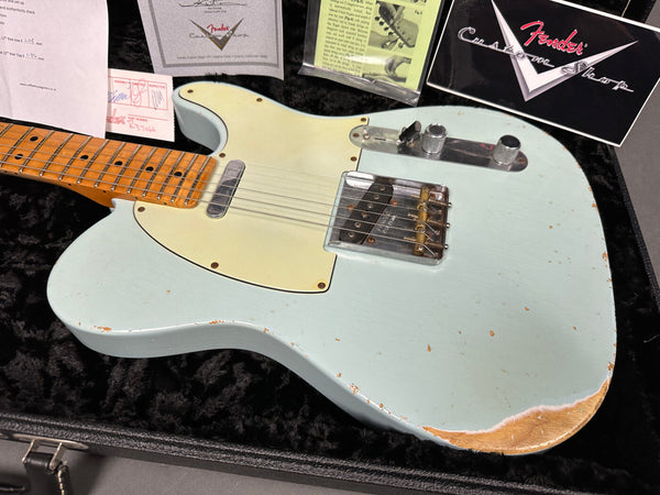 Fender Custom Shop vintage-style Telecaster electric guitar in light blue finish with worn relic details, maple neck, and cream pickguard displayed in plush black guitar case with Fender Custom Shop paperwork and authenticity certificates.