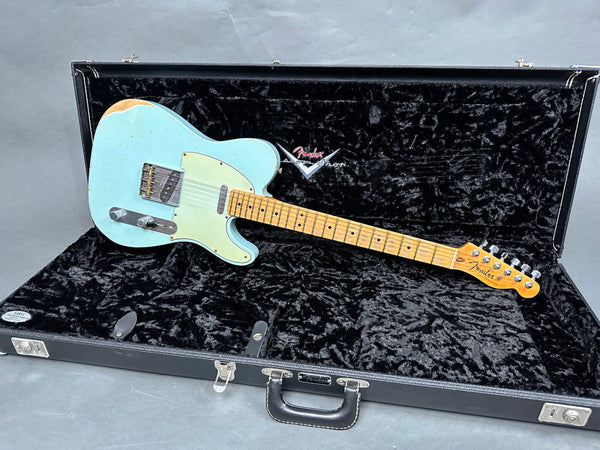 Fender Telecaster electric guitar in light blue with worn finish resting in open black Fender hard case with plush interior lining