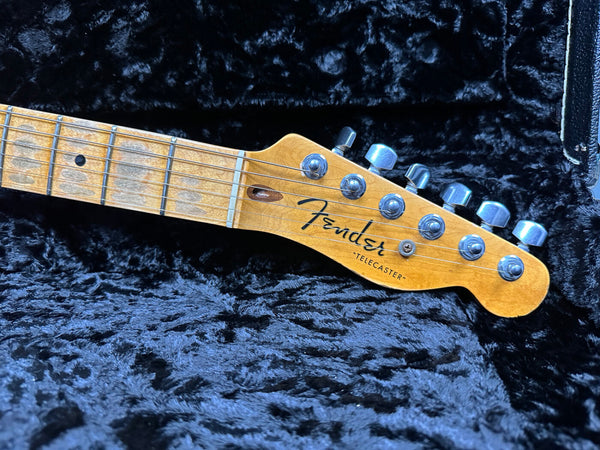 Close-up of Fender Telecaster electric guitar headstock and maple fretboard with tuning pegs in black plush guitar case
