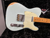 Close-up of vintage Fender Telecaster electric guitar with worn light blue finish and maple fretboard resting in black plush Fender custom shop case