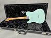 Back of vintage Fender electric guitar in surf green finish with maple neck shown in open black plush-lined Fender Custom Shop hard case on gray background