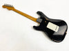 Black electric guitar with wooden neck and vintage wear and tear on body, back view on white background