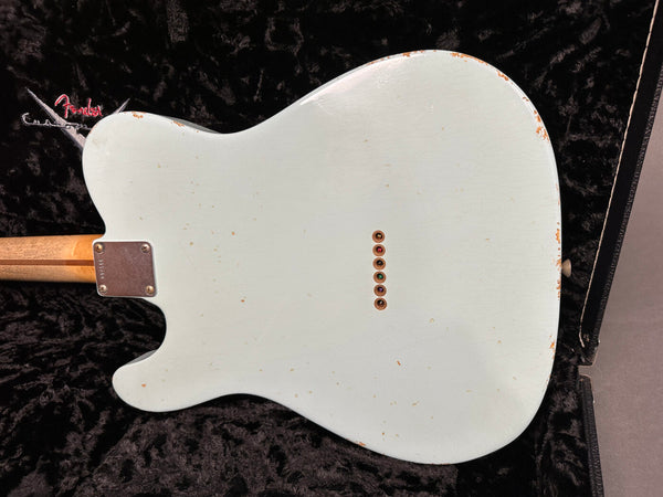 Back view of vintage-style Fender Telecaster electric guitar with worn white finish and six string ferrules, resting in black plush-lined hard case