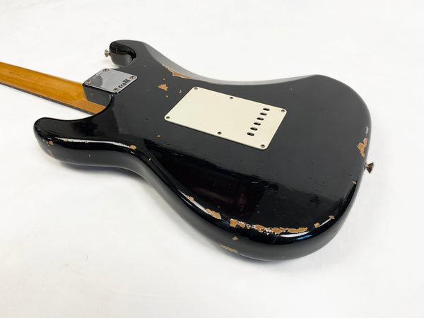 Back of worn black electric guitar body with chip and scratch detailing, maple neck, and white backplate on white background