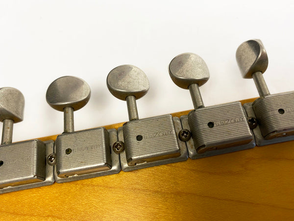 Close-up of vintage guitar tuning pegs with metal tuning machines on light wood headstock against white background