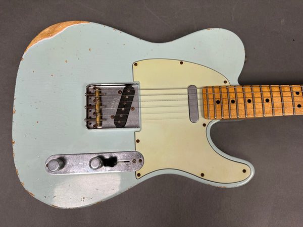 Light blue vintage Fender Telecaster electric guitar with maple neck and aged pickguard showing wear and relic details on gray background