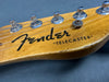 Close-up of vintage Fender Telecaster guitar headstock showing tuning pegs, strings, and logo on natural wood finish against gray background