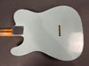 Back of vintage light blue electric guitar body with wood neck and string ferrules visible and distressed finish