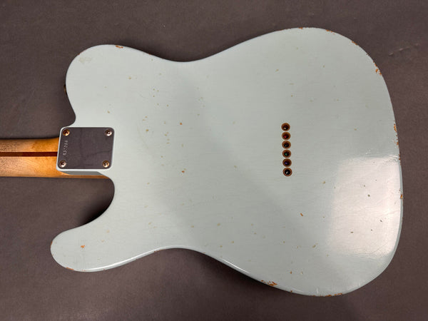 Back of vintage light blue electric guitar body with wood neck and string ferrules visible and distressed finish