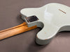 Close-up rear view of white electric guitar body and neck joint showing wood grain neck and metal neck plate with screws and relic finish details